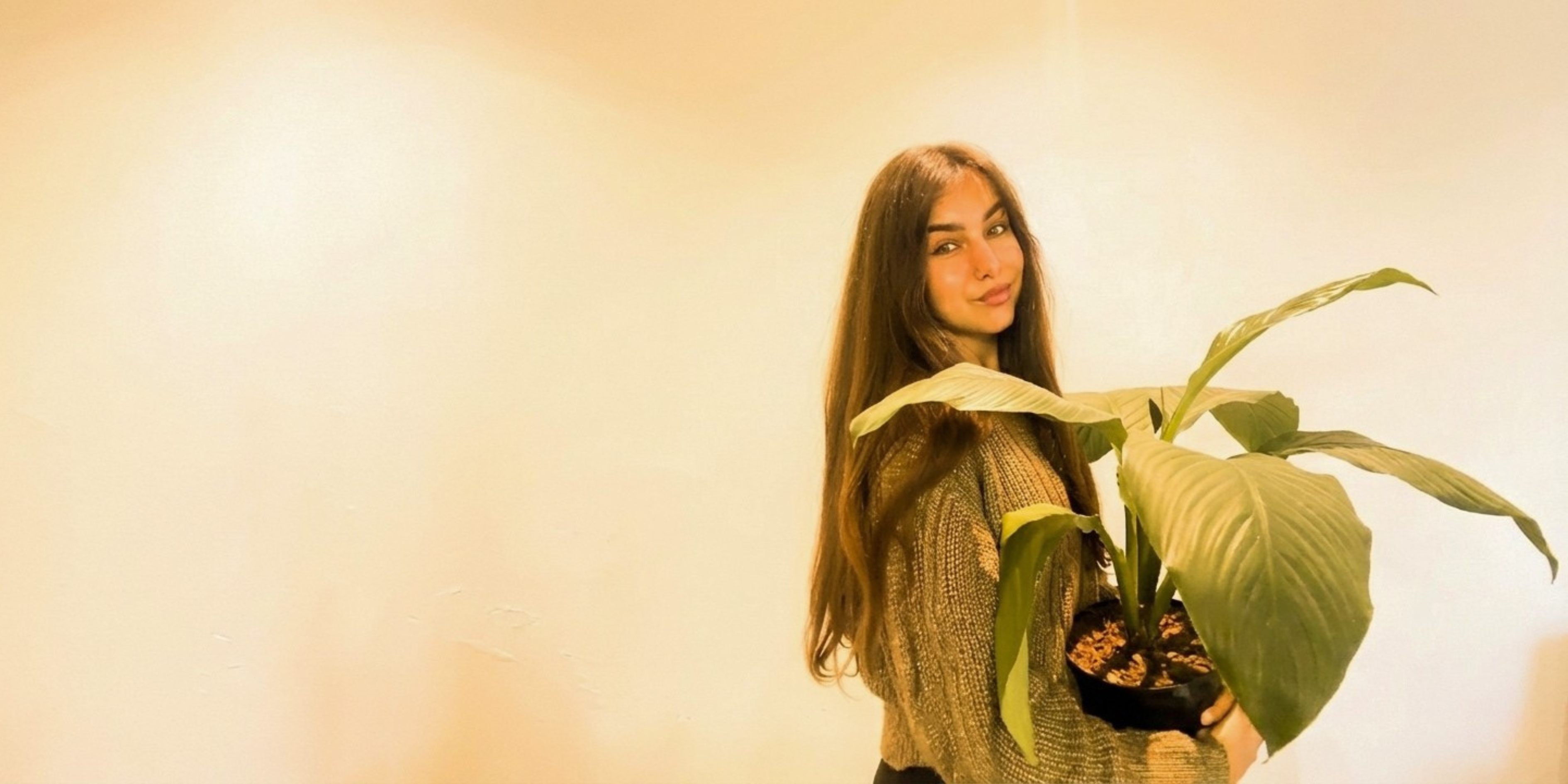 Woman holding a plant against a plain background